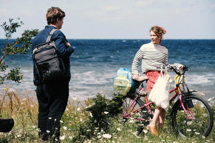 Une fille à vélo et un garçon se parle dans la nature au bord de l'eau
