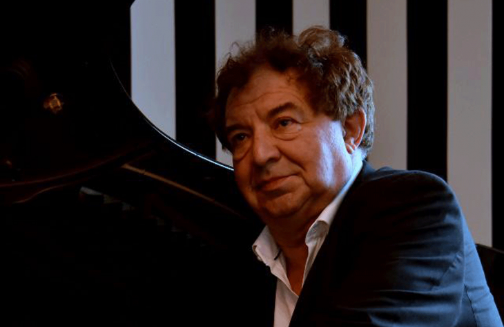 Un homme en veste noire, près d'un piano noir