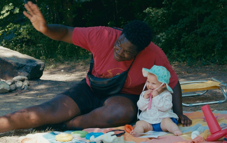 Un homme et un bébé assis à la plage, faisant coucou
