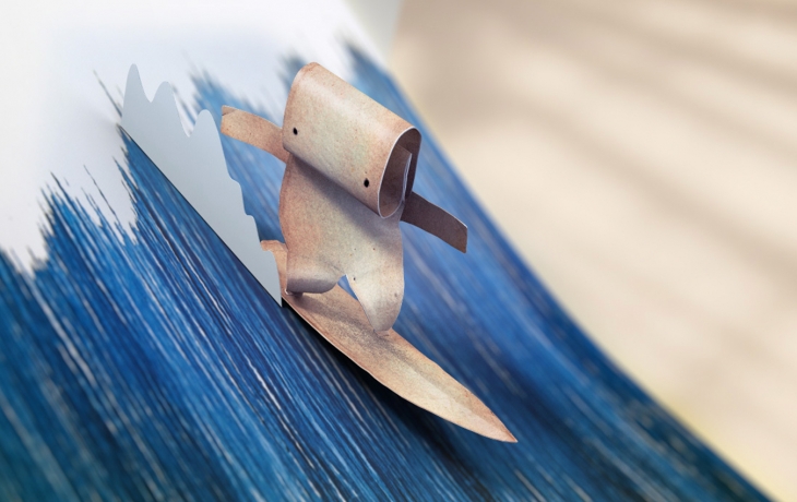 Un personnage en papier fait du surf sur une vague en papier.