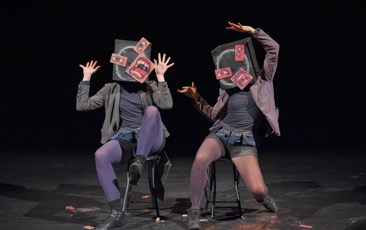 Les boîtes sur les têtes se transforment en visages surréalistes : des yeux, des bouches et des oreilles découpés sont collés de manière déstructurée, formant des expressions exagérées. Les corps des interprètes sont figés dans des postures expressives, presque caricaturales, évoquant la surprise ou la panique. L’univers visuel oscille entre collage dadaïste et théâtre gestuel.