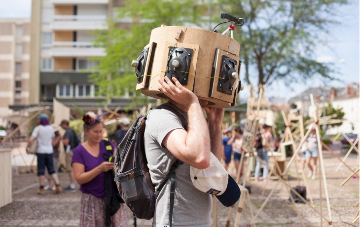 Homme dans une sorte de boite en bois avec des enceintes