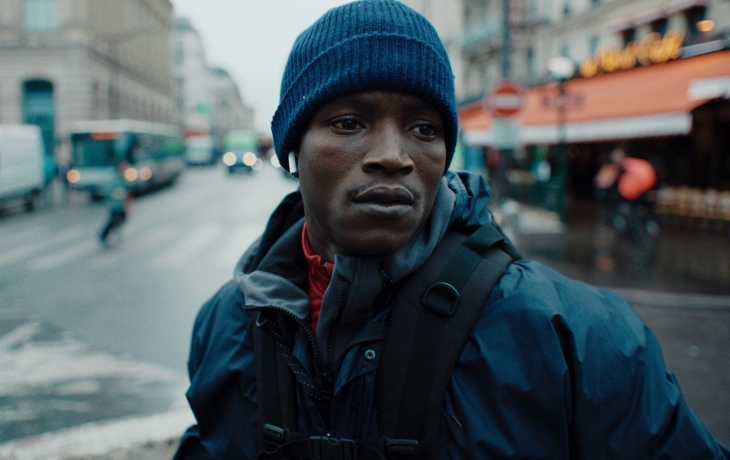 Plan serré sur le visage de Souleymane dans les rues de Paris.