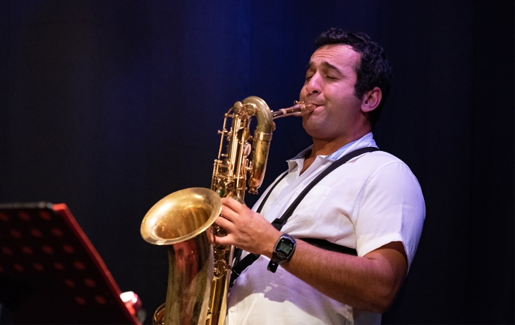 Plan serré sur Sofiane Messabih qui joue du saxophone.