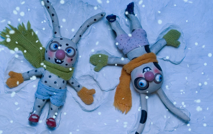 Des lapins avec des vêtements d'hiver font les anges dans la neige