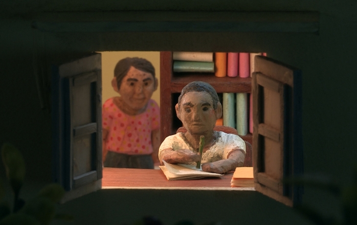 Dans l'encadrement d'une fenêtre, deux petits personnages en argiles. L'un des deux écrit une lettre devant la fenêtre.