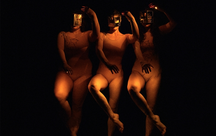 Les 3 interprètes en train de danser avec des masques sur le visage
