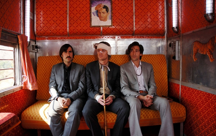 Les trois frères sont dans le Darjeeling, un train en Inde. Ils sont assis dans une cabine orange. Celui qui est au milieu porte des bandages sur la tête et le visage. Les trois portent des costumes.