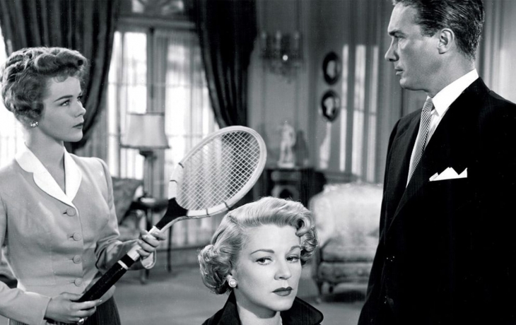 A gauche, la jeune fille tient une raquette de tennis dans ses mains et elle regarde l'homme qui se tient à droite et qui la regarde aussi. Au centre, la tête de la mère dépasse du cadre, on devine qu'elle est assise. La construction de l'image fait qu'on dirait que la jeune fille tape sa raquette dans la tête de la mère.