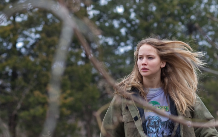 Une jeune femme les cheveux au vent marche dans la nature. Elle semble chercher quelque chose ou quelqu'un.