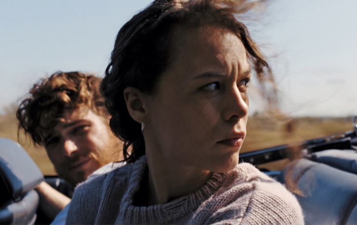 En voiture, une femme à côté d'un homme se retourne, le regard dur