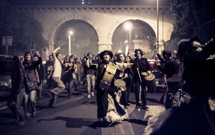 Des musiciens habillés en morts-vivants déambulent avec des passants dans une rue 