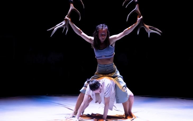 Une danseuse tient des bois de cerf dans ses mains au dessus d'une autre danseuse