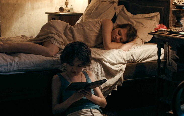 Femme au lit, son fils à terre lit une histoire