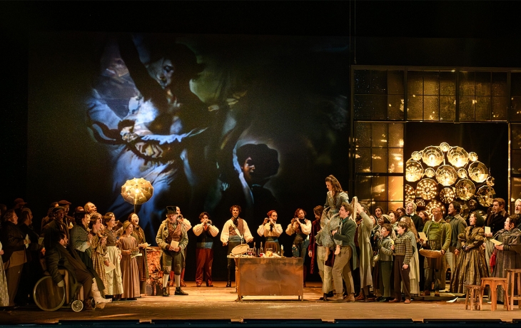 Scène de l'opéra de Dijon où les chanteurs sont en costumes d'époque, "La liberté guidant le Peuple" projetée sur un écran 
