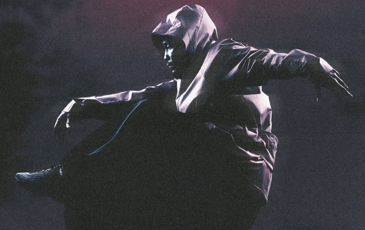 Un danseur habillé de noir danse au sol 