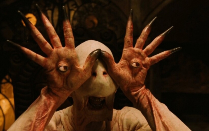 Un alien met ses mains devant lui, à l'intérieur, des yeux