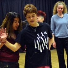 La chorégraphe montre un mouvement de levée du bras gauche à une femme, en lui tenant le poignet.