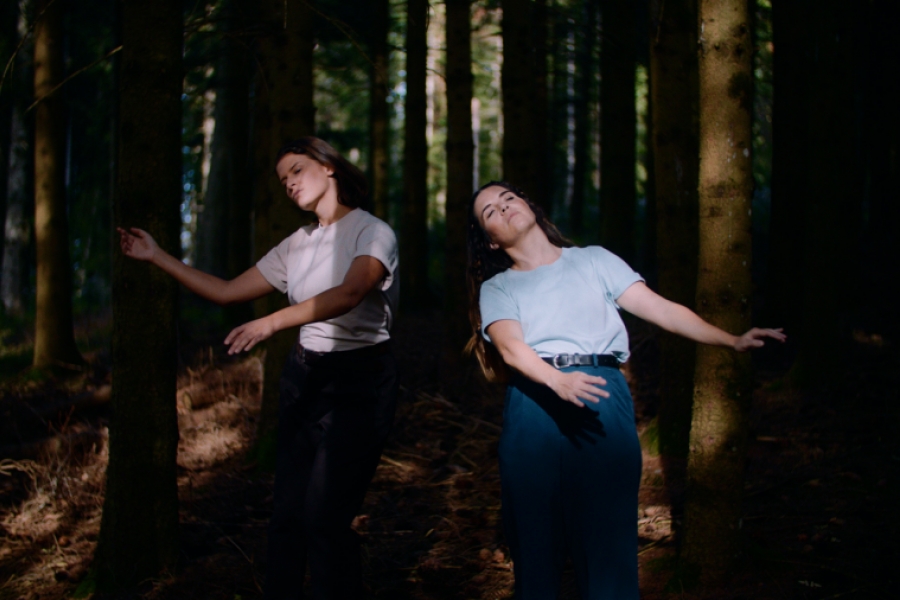 Deux femmes qui semblent danser dans une forêt, elles sont éclairées par le soleil