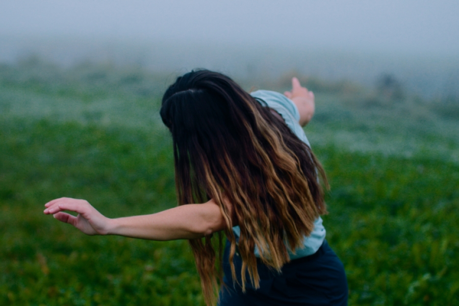 Une femme semble danser dans un champs brumeux, elle nous tourne le dos, on ne voit pas son visage