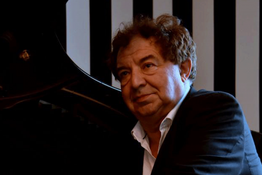 Un homme en veste noire, près d'un piano noir