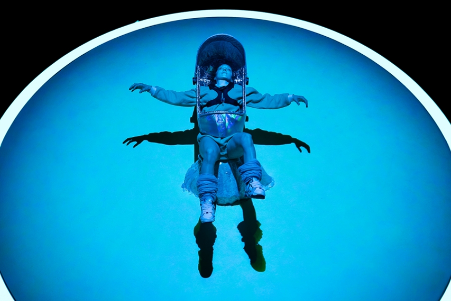 Au centre d'un cercle lumineux, un femme au costume futuriste allongée