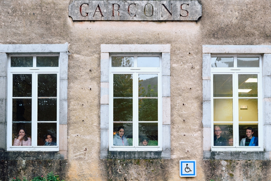 Maison avec derrière les fenêtres, des enfants. Un symbole handicapé est place sur le mur extérieur.