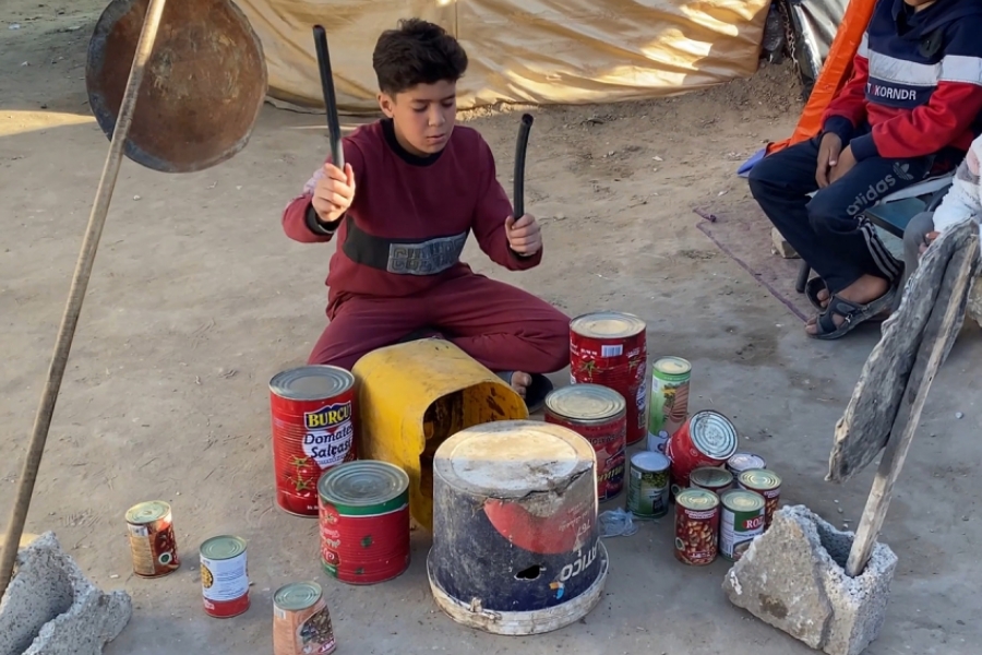 Un enfant jouant de la musique par terre, sur des boîtes retournées
