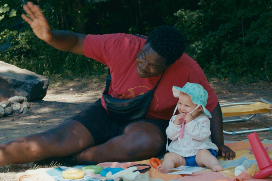 Un homme et un bébé assis à la plage, faisant coucou