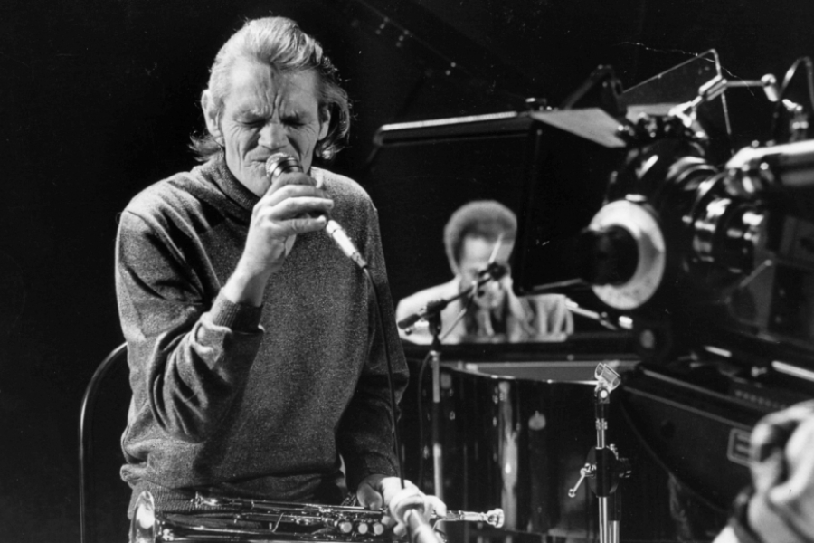 Photo de scène en noir et blanc où le chanteur est en gros plan, micro à la bouche
