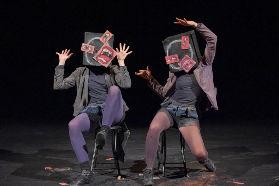 Les boîtes sur les têtes se transforment en visages surréalistes : des yeux, des bouches et des oreilles découpés sont collés de manière déstructurée, formant des expressions exagérées. Les corps des interprètes sont figés dans des postures expressives, presque caricaturales, évoquant la surprise ou la panique. L’univers visuel oscille entre collage dadaïste et théâtre gestuel.