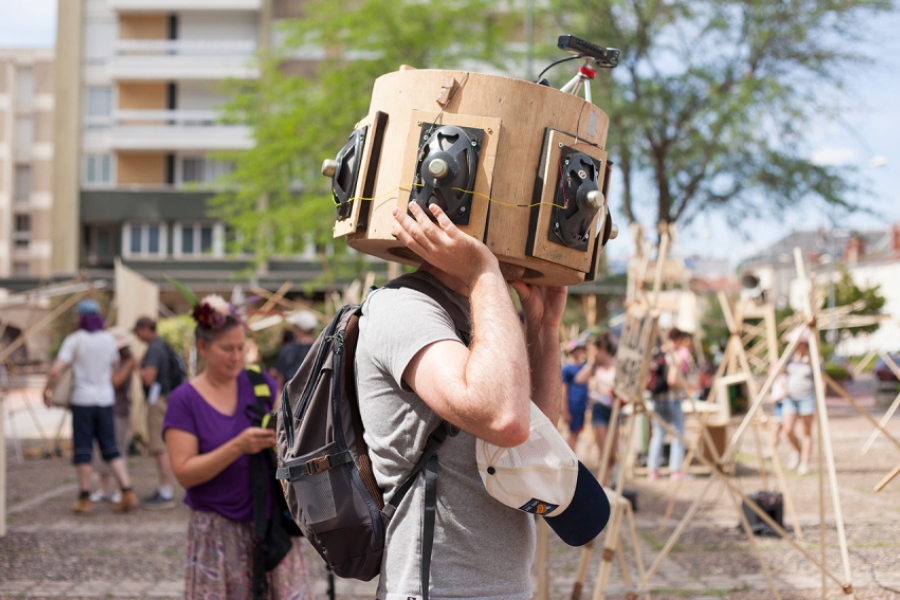 Homme dans une sorte de boite en bois avec des enceintes