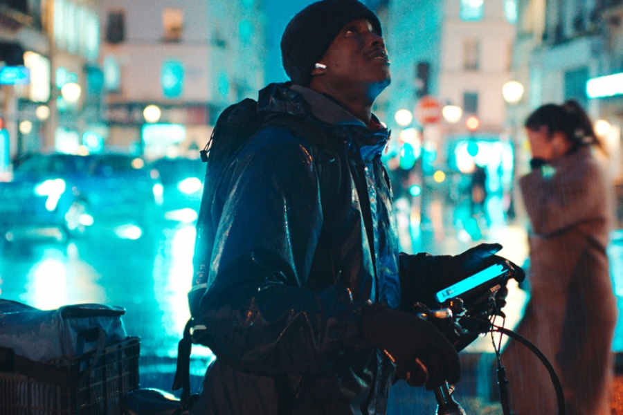 Souleymane est sur son vélo dans les rues de Paris et regarde en l'air.