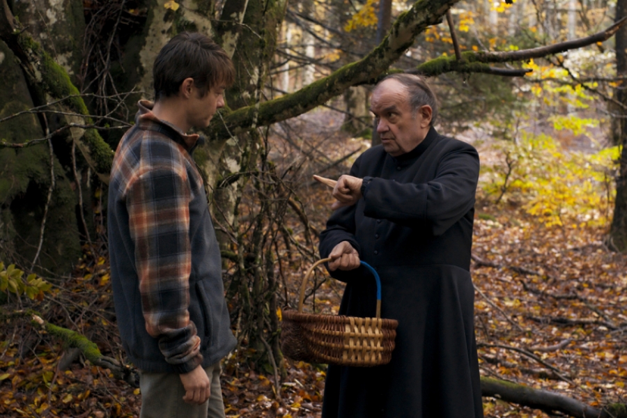 L'abbé et Jérémie sont dans la forêt, l'abbé porte un panier et pointe du doigt Jérémie en lui parlant.