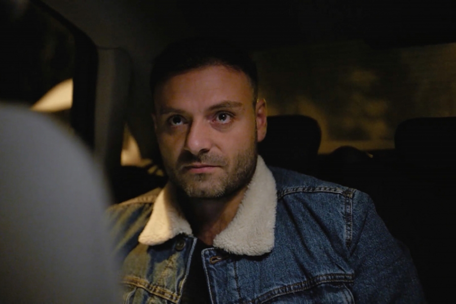 Un homme assis à l'arrière d'un Uber, regarde devant lui d'un air méfiant.