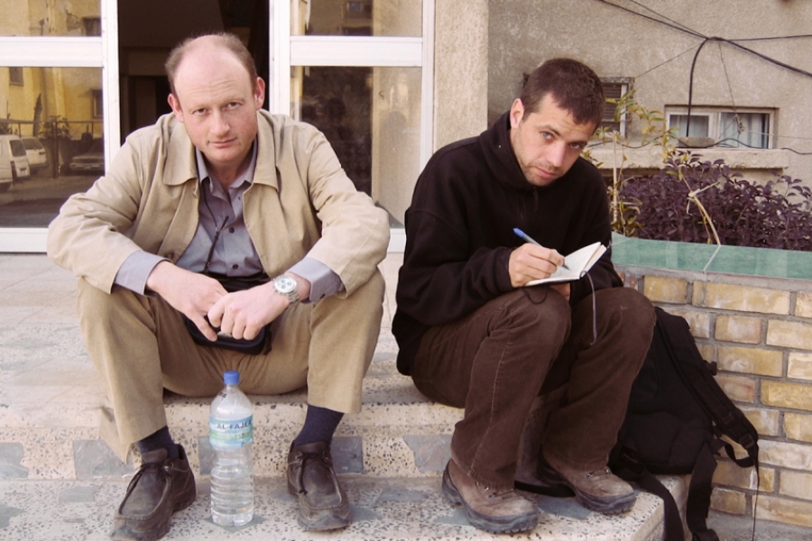 Deux reporters sont assis sur des marches dehors. 