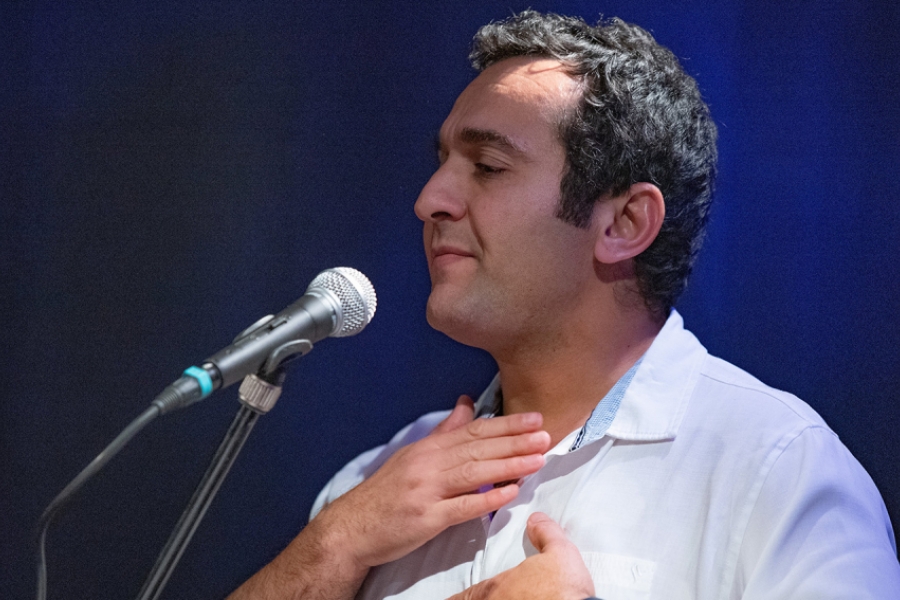 Plan seré sur Sofiane Messabih qui chante dans un micro sur scène. 