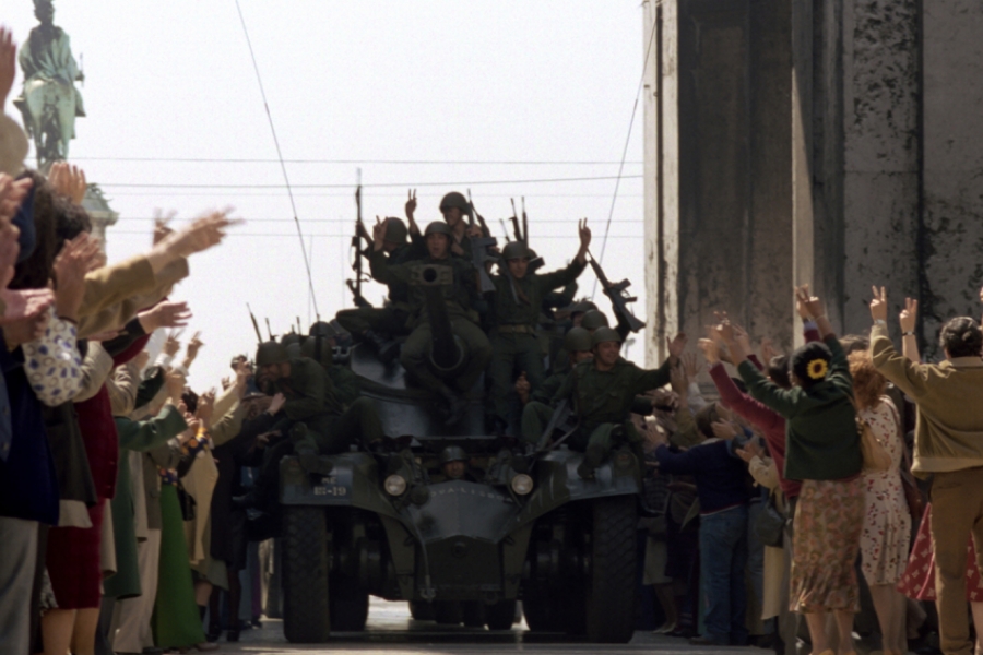 Une foule acclame un char et des soldats dans la rue.