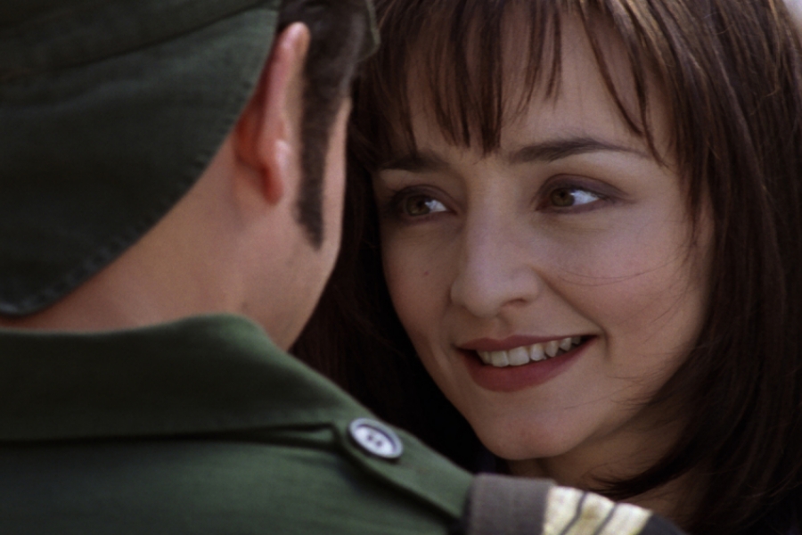 Gros plan sur le visage de Maria de Medeiros qui sourit au soldat qui lui, est de dos.
