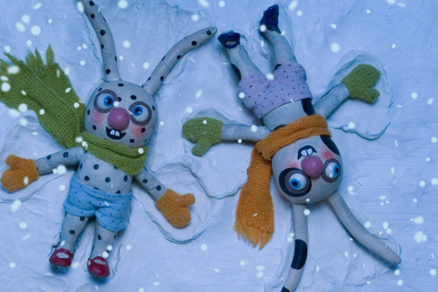 Des lapins avec des vêtements d'hiver font les anges dans la neige