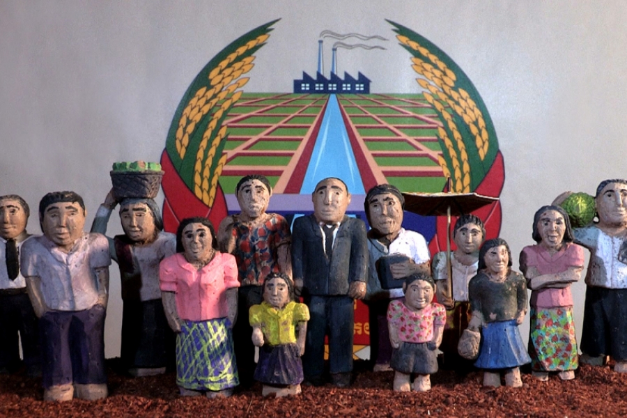 Des personnages en argiles qui semble composées une famille se tiennent devant la caméra, comme pour faire une photo de famille. Derrière eux est dressé un symbole avec un dessin d'usine. 