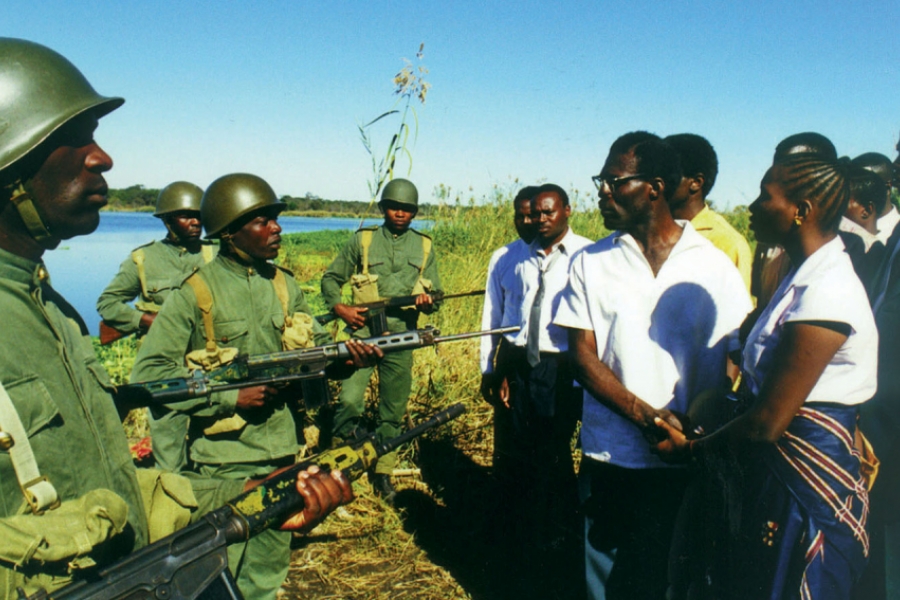 Dans la nature, un groupe de soldat pointent leurs armes sur des civils.