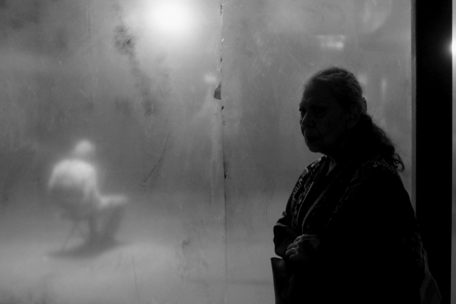 Femme dans l'ombre derrière une vitre où un homme est gardé attaché