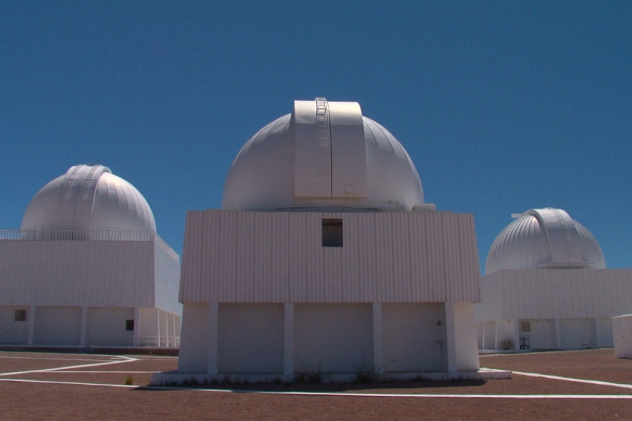 Dans le désert, trois structures d'astronomie sont implantées dans le sable.