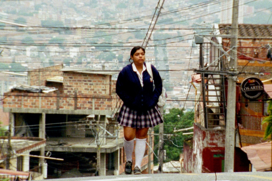 Une jeune femme en tenue d'écolière au milieu d'un quartier colombien