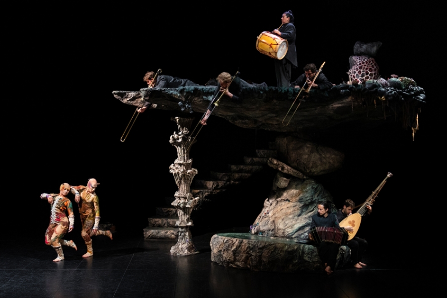 2 danseurs sur scènes avec au dessus d'un décor, les musiciens
