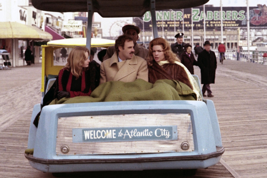 Deux femmes entourent un de deux frère, dans une petite voiture touristique où il est écrit "Bienvenue à Atlantic City"