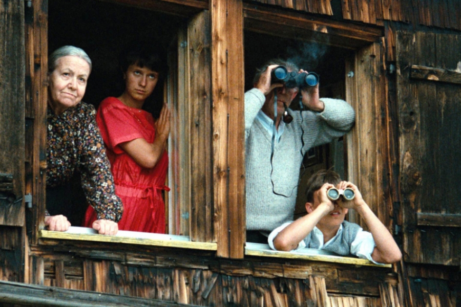 La famille regarde par la fenêtre. Deux d'entre eux ont des jumelles.