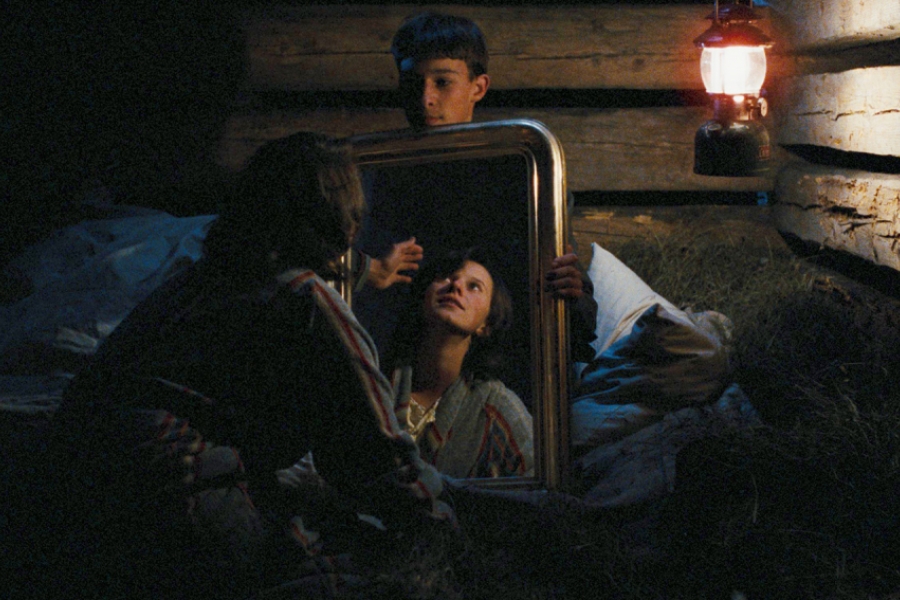 Dans une chambre éclairée par une lampe à huile, le Boueb tient un miroir tournée vers la fille qui est de dos, mais où l'on voit son relet