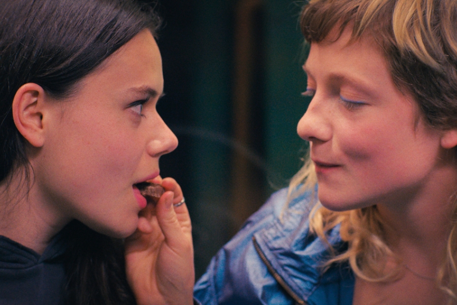 Deux jeunes femmes se regardent. La blonde porte de la nourriture à la bouche de la brune.